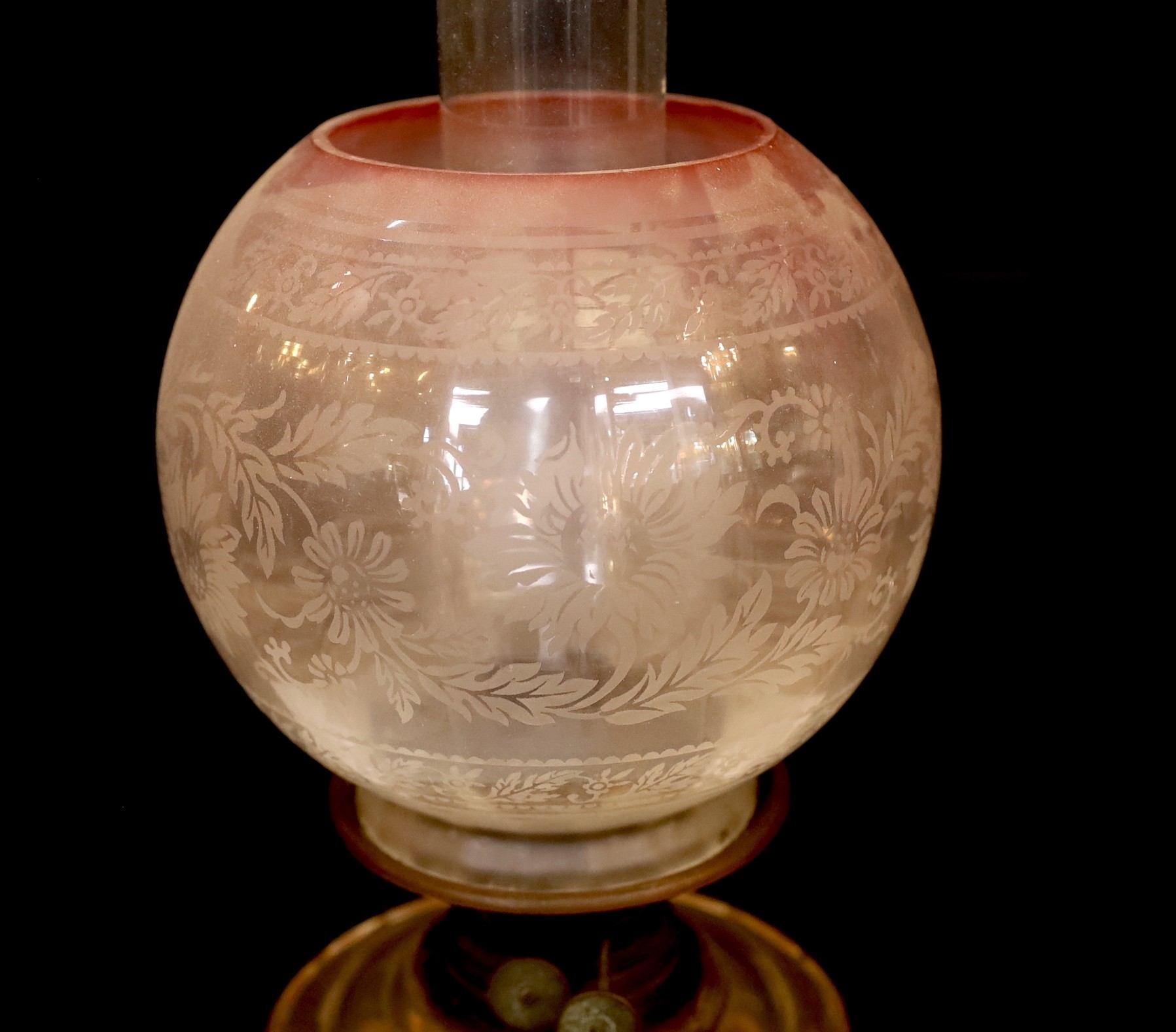 An Edwardian brass oil lamp with cut glass reservoir and pink tinted etched glass globe and flue, height overall 65cm